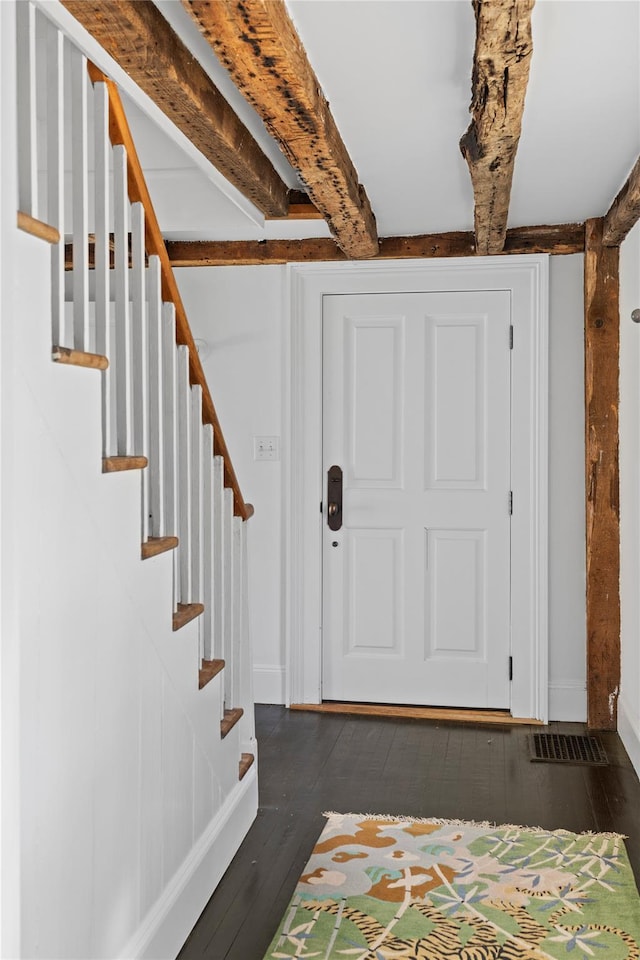 entrance foyer with stairs, beam ceiling, wood finished floors, and baseboards