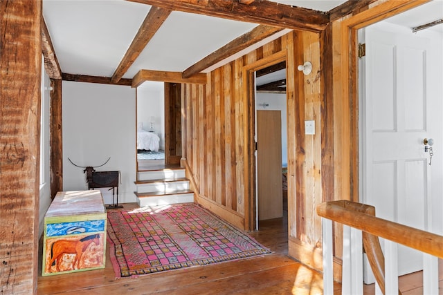 corridor with beamed ceiling, stairway, hardwood / wood-style floors, and wood walls