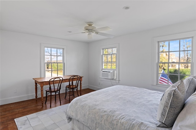 bedroom with multiple windows, cooling unit, baseboards, and wood finished floors