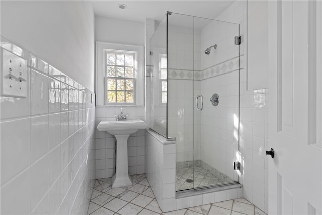 full bathroom with a shower stall, tile walls, and marble finish floor
