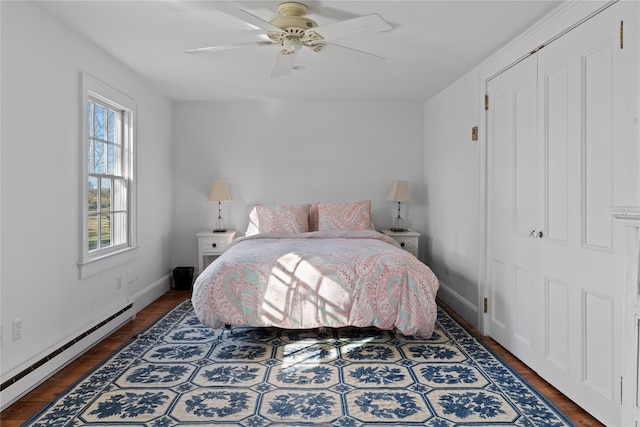 bedroom with a baseboard heating unit, wood finished floors, baseboards, and a ceiling fan