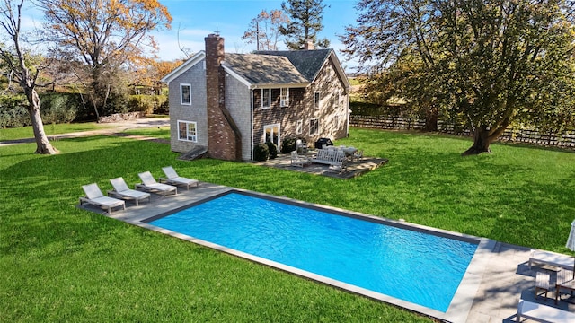 outdoor pool with a patio, a lawn, and fence