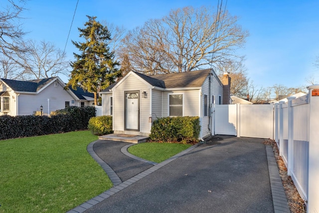 view of front of property featuring a front yard, a gate, fence, and a chimney