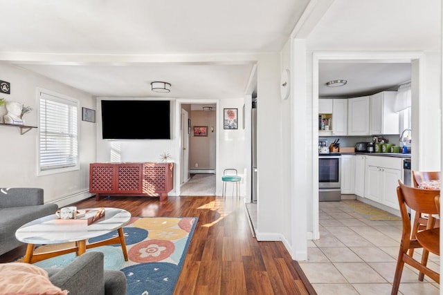 living area with baseboard heating, baseboards, a baseboard heating unit, and light wood-style floors