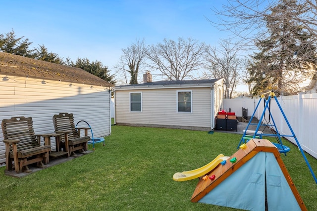 rear view of property featuring a fenced backyard, a chimney, and a yard