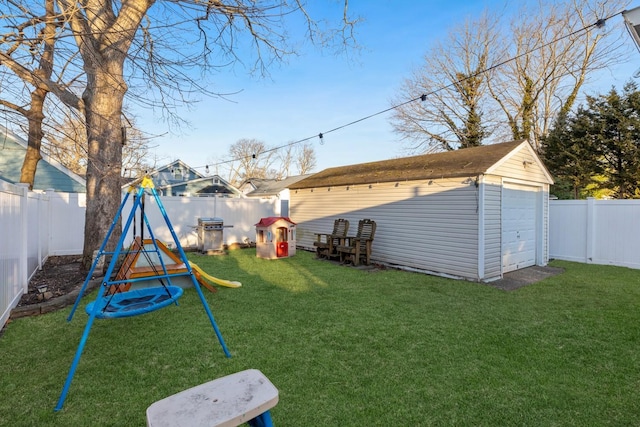 view of yard with an outbuilding, a playground, a fenced backyard, and a garage