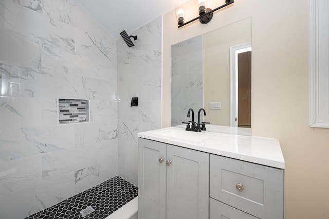 full bathroom featuring tiled shower and vanity