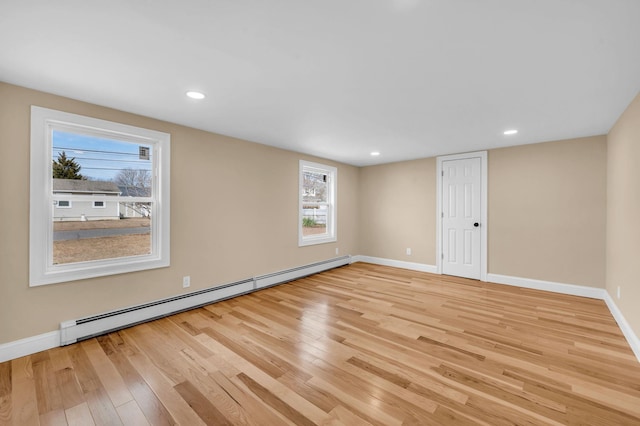 empty room with light wood-type flooring, baseboards, and a baseboard radiator