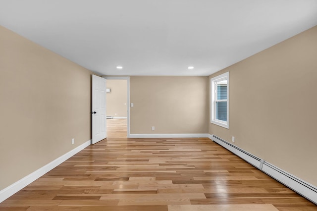 spare room with a baseboard heating unit, recessed lighting, light wood-style floors, and baseboards