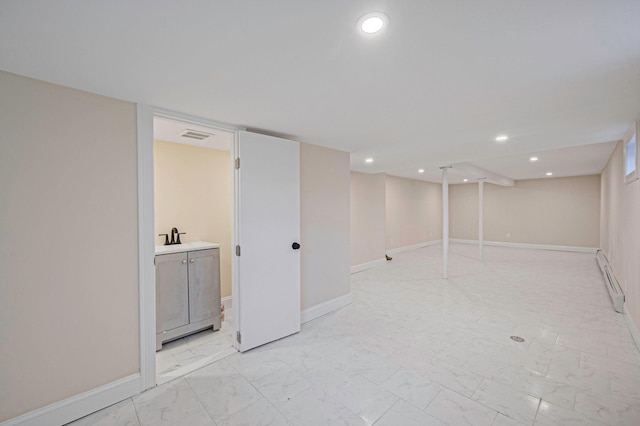 finished basement with marble finish floor, a sink, recessed lighting, a baseboard radiator, and baseboards