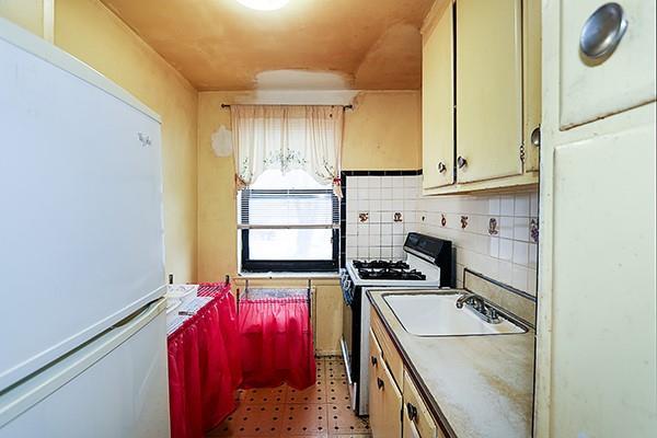 kitchen featuring tasteful backsplash, light floors, freestanding refrigerator, gas stove, and a sink