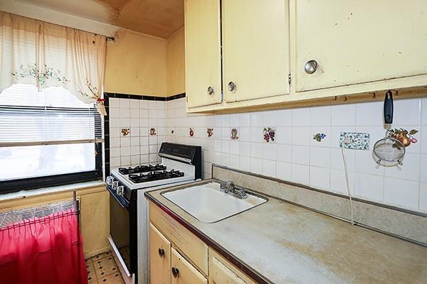 kitchen featuring white gas stove, decorative backsplash, light countertops, and a sink