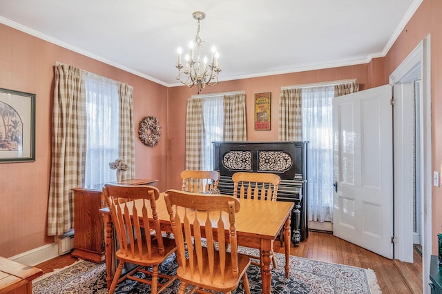 dining space with a chandelier, light wood-style flooring, crown molding, and baseboards