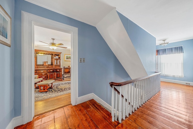 hallway featuring an upstairs landing, baseboards, and hardwood / wood-style floors