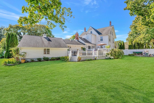 back of property featuring a yard, fence, a chimney, and a wooden deck