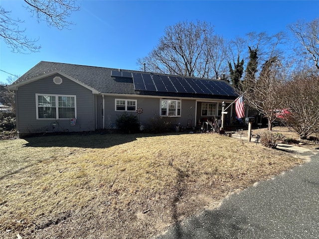 view of front of house featuring solar panels and a front lawn