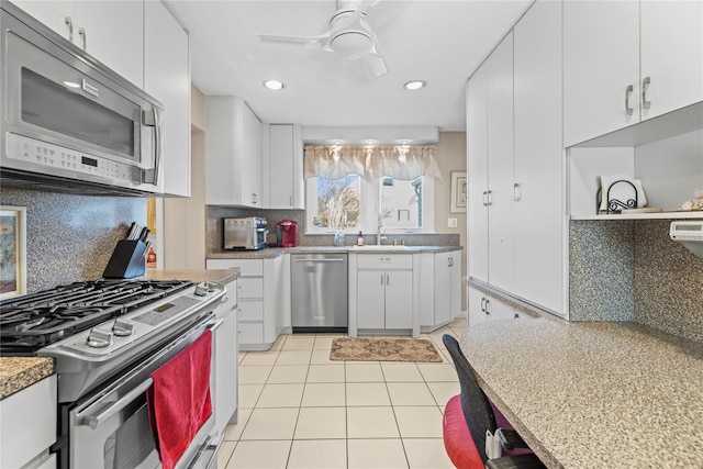 724 Thrush Ave, West Hempstead, NY 11552 - kitchen featuring appliances with stainless steel finishes, light tile patterned floors, backsplash, white cabinets, and a ceiling fan