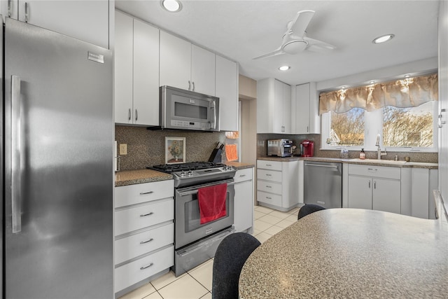 724 Thrush Ave, West Hempstead, NY 11552 - kitchen featuring appliances with stainless steel finishes, a sink, white cabinets, decorative backsplash, and light tile patterned flooring