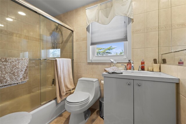 724 Thrush Ave, West Hempstead, NY 11552 - full bath with tile walls, toilet, bath / shower combo with glass door, vanity, and tile patterned flooring