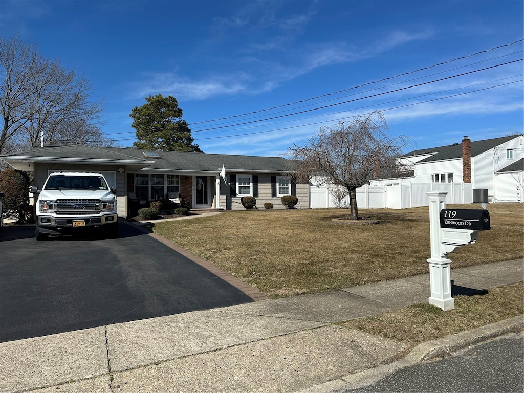 ranch-style home with aphalt driveway, an attached garage, a front yard, and fence