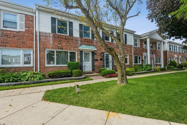 townhome / multi-family property with brick siding and a front yard