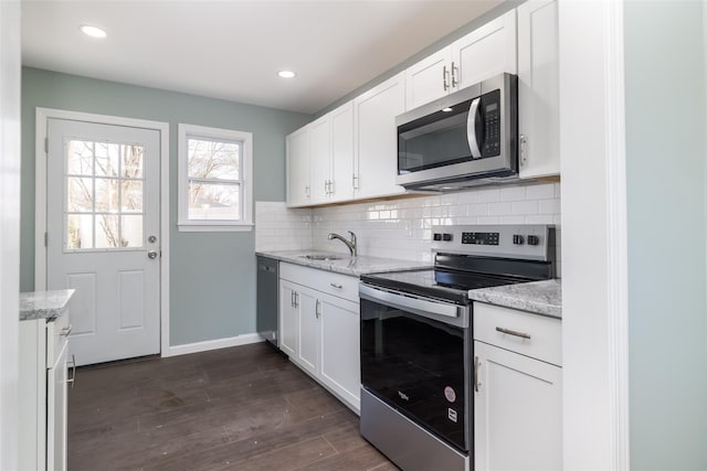 kitchen with a sink, stainless steel appliances, dark wood-type flooring, white cabinetry, and tasteful backsplash