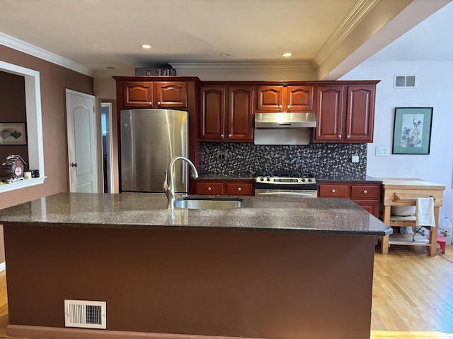 kitchen with visible vents, a sink, under cabinet range hood, appliances with stainless steel finishes, and decorative backsplash