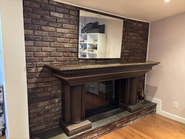 details featuring a brick fireplace, baseboards, and wood finished floors