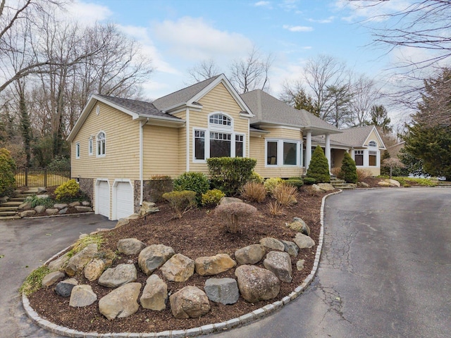 view of front of property featuring aphalt driveway, an attached garage, fence, and a shingled roof