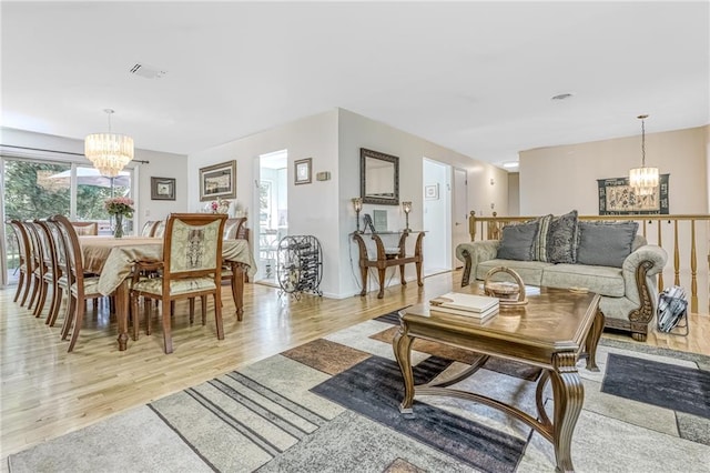 living area with visible vents, a notable chandelier, and light wood finished floors