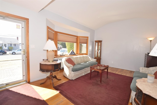 living room featuring baseboards, wood finished floors, and vaulted ceiling