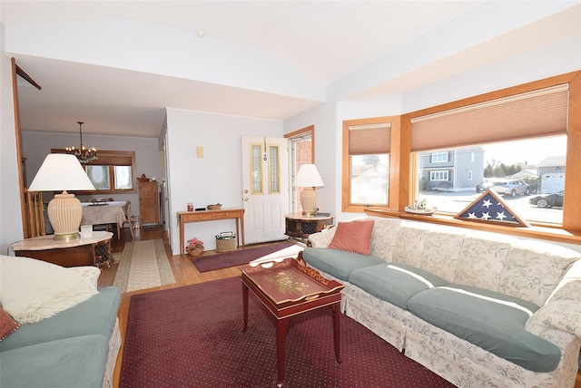 living room featuring vaulted ceiling, a notable chandelier, and wood finished floors