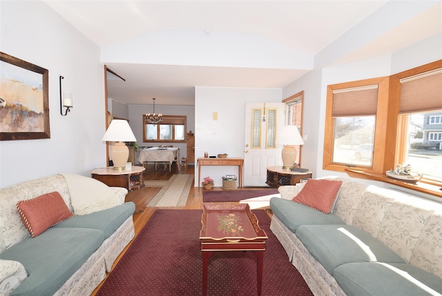 living area with a chandelier, a wealth of natural light, and vaulted ceiling