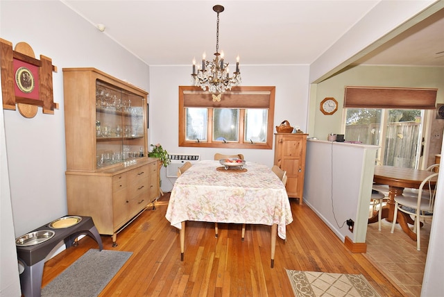 dining space with an inviting chandelier, light wood-style floors, and ornamental molding