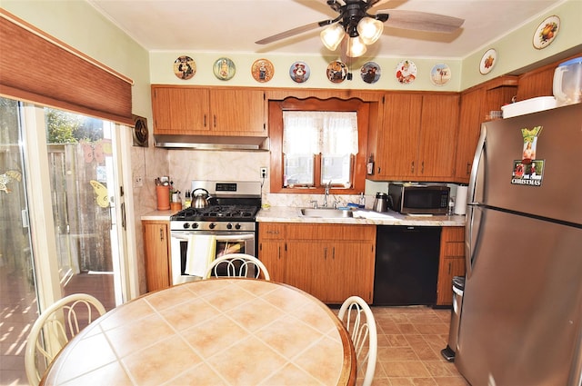 kitchen featuring exhaust hood, appliances with stainless steel finishes, light countertops, and a sink