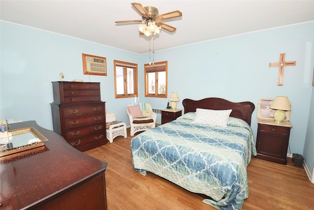 bedroom featuring a ceiling fan, light wood-type flooring, and a wall mounted air conditioner