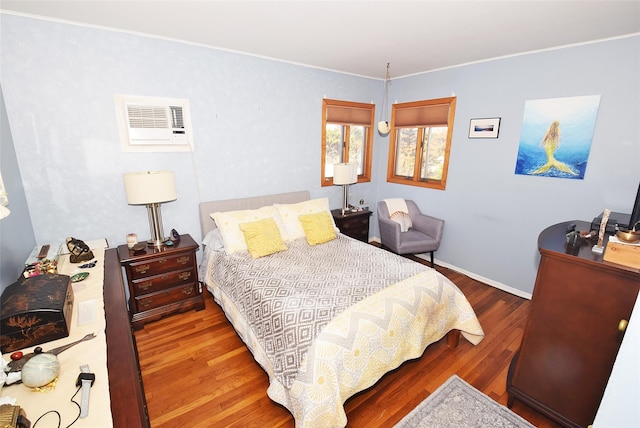 bedroom with wood finished floors, crown molding, and a wall unit AC