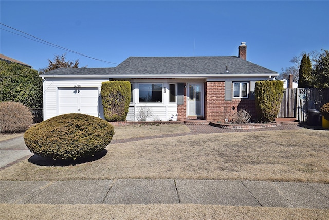 ranch-style house featuring brick siding, an attached garage, a chimney, and a shingled roof