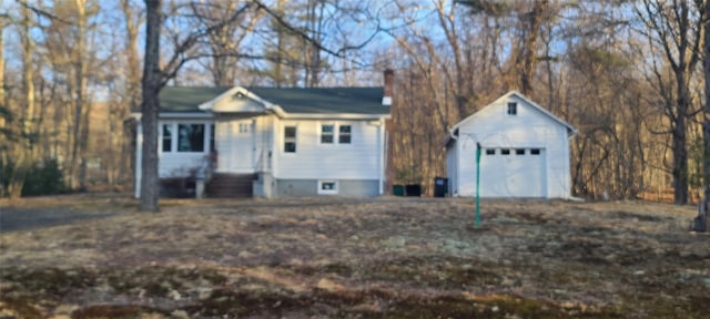 view of front facade featuring a garage, entry steps, a chimney, and an outbuilding