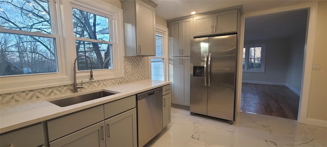kitchen with tasteful backsplash, a sink, stainless steel appliances, gray cabinets, and marble finish floor