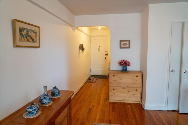 hallway featuring arched walkways and hardwood / wood-style floors