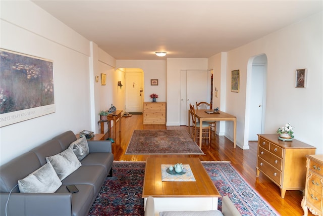 living area featuring baseboards, arched walkways, and wood finished floors