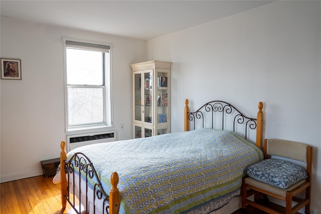 bedroom with baseboards, radiator, and wood finished floors