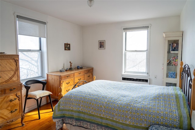 bedroom featuring multiple windows, wood finished floors, and a wall unit AC