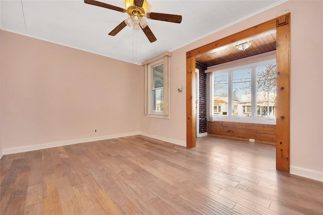 unfurnished room with ceiling fan, baseboards, light wood-style flooring, and crown molding