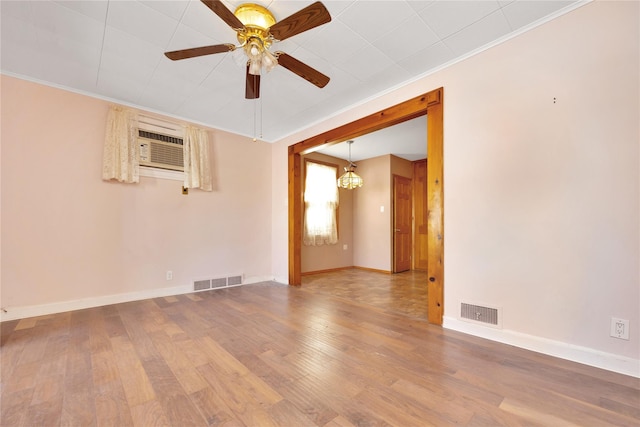 empty room featuring visible vents, ornamental molding, ceiling fan, and wood finished floors