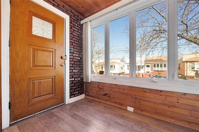 entrance foyer featuring wooden ceiling, wood finished floors, a residential view, and brick wall