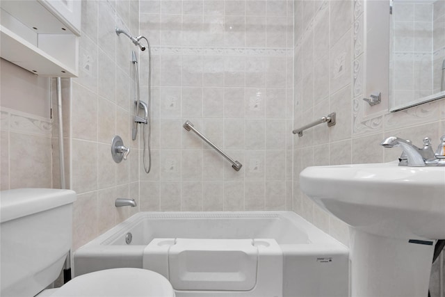 bathroom with toilet, a sink, tile walls,  shower combination, and decorative backsplash