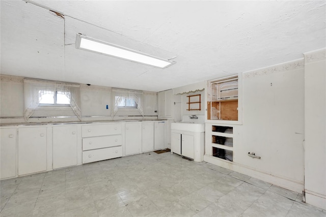 kitchen featuring white cabinetry, washer / dryer, and light floors