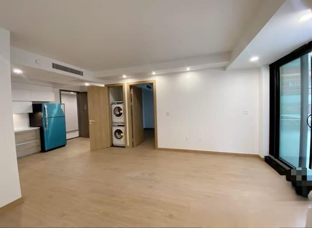 unfurnished room featuring visible vents, stacked washing maching and dryer, recessed lighting, light wood-style floors, and baseboards